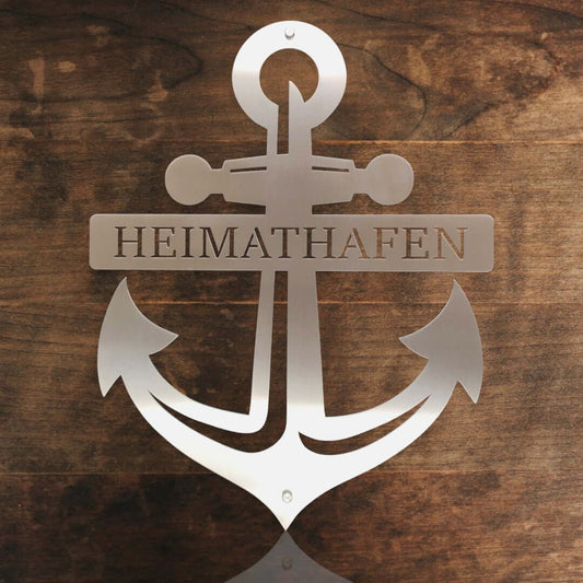 maritime edelstahl wanddeko anker mit schriftzug heimathafen vor einer holzwand